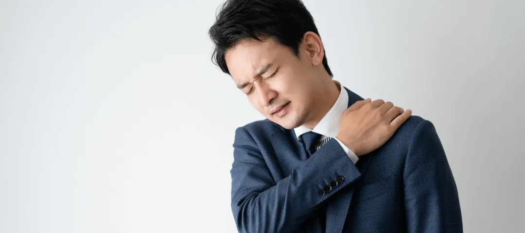 肩を押さえている男性の画像